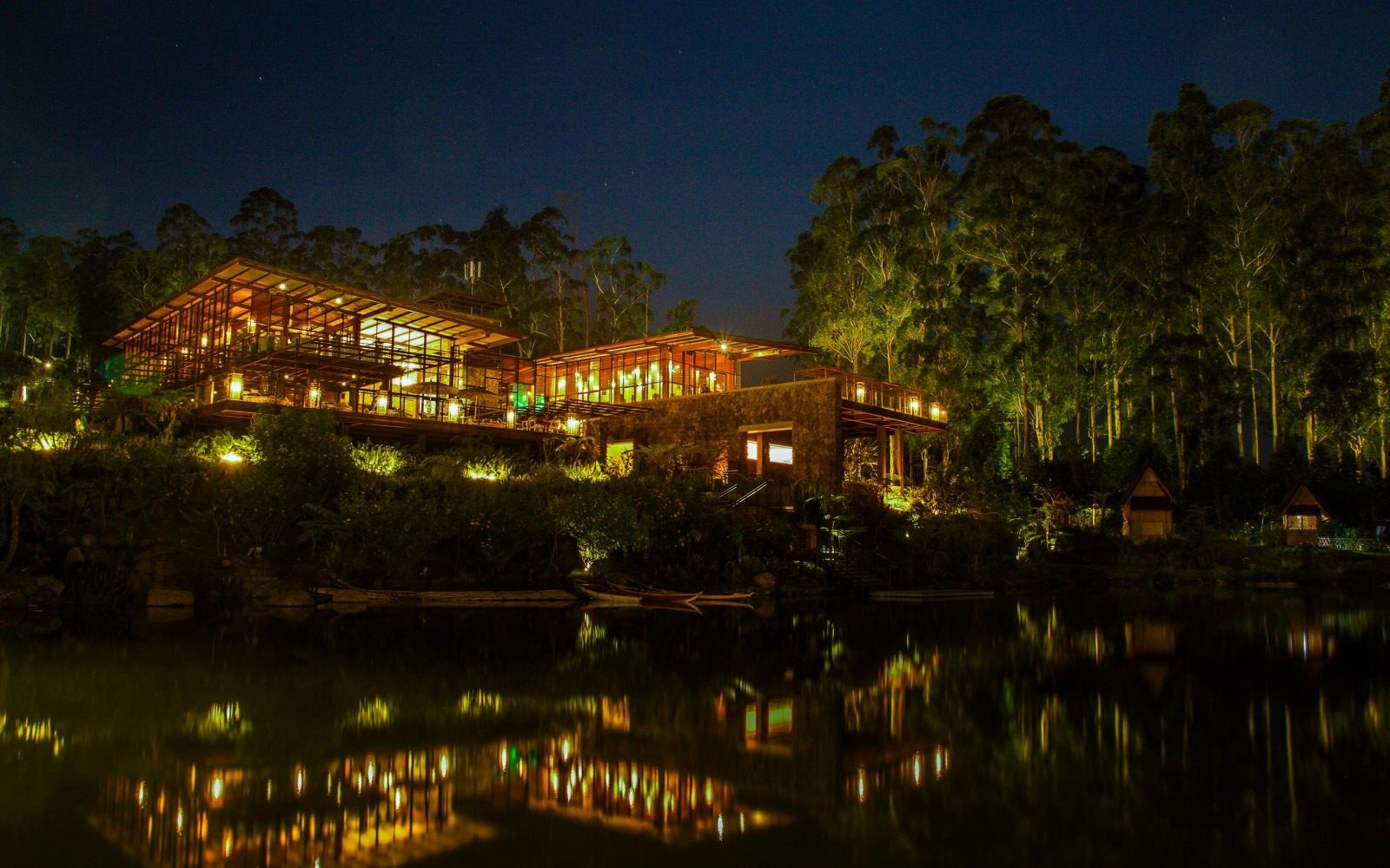 Waterfront home lit by outdoor landscape lighting at night