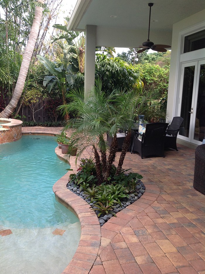 Curved pool with tropical planting and brick patio