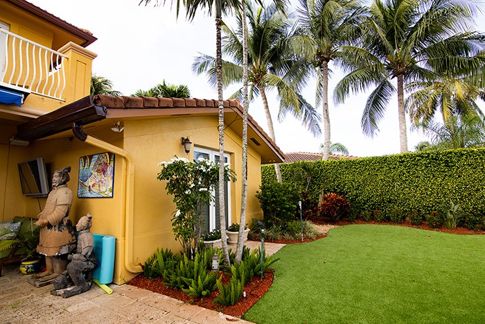 Immaculate green lawn at a yellow South Florida home with palms